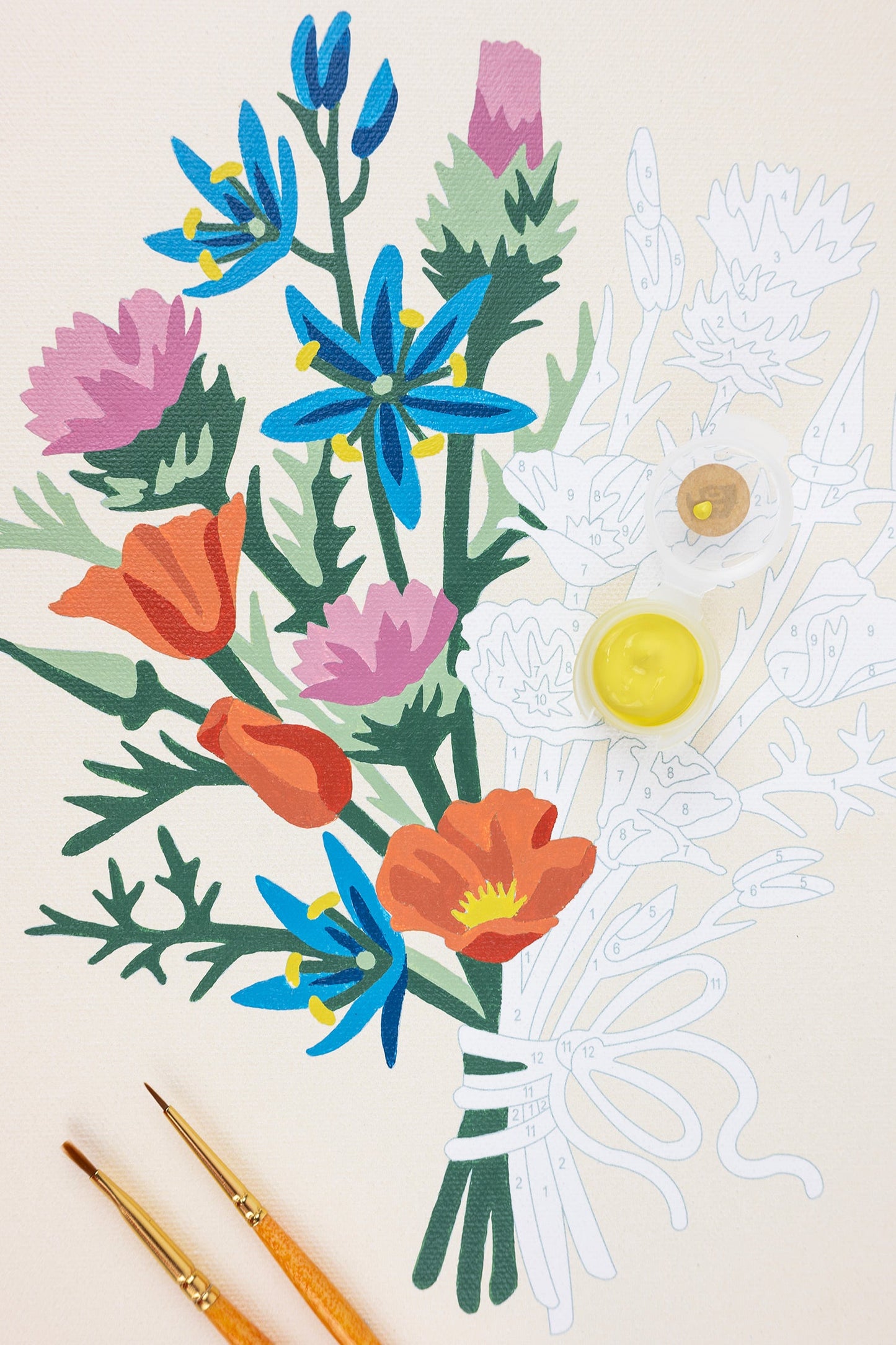 Colorful floral arrangement with paintbrushes on a beige background