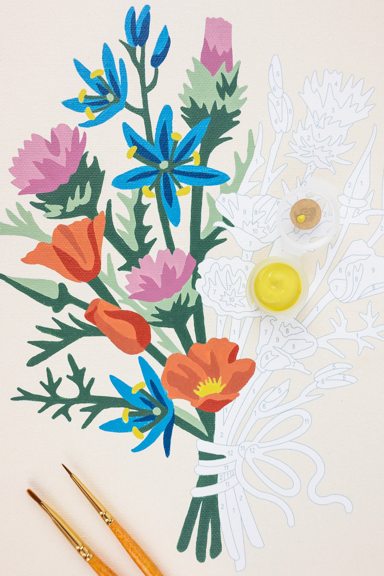 Colorful floral arrangement with paintbrushes on a beige background